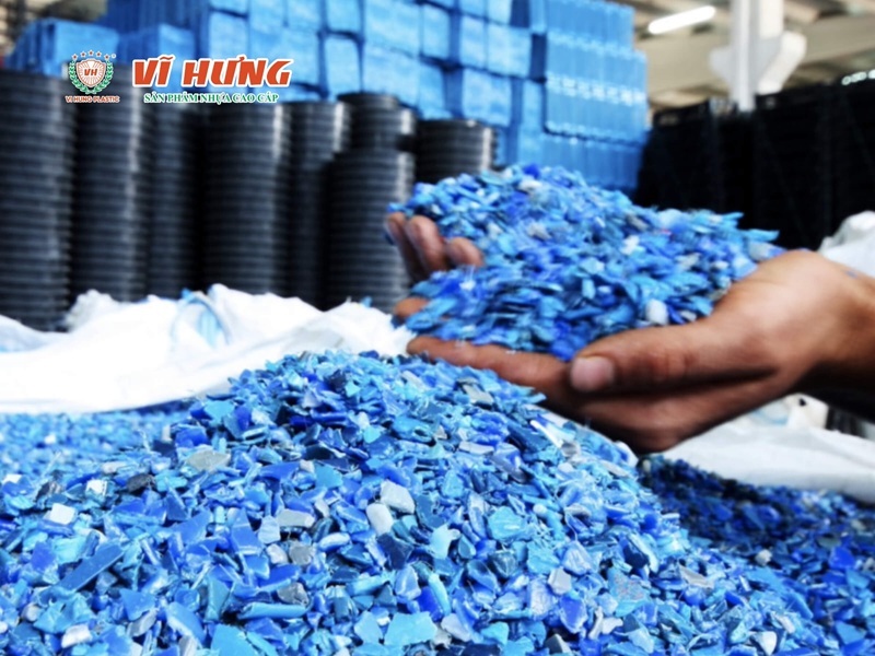 Công nhân cầm hạt nhựa tái sinh màu xanh tại nhà máy sản xuất nhựa công nghiệp