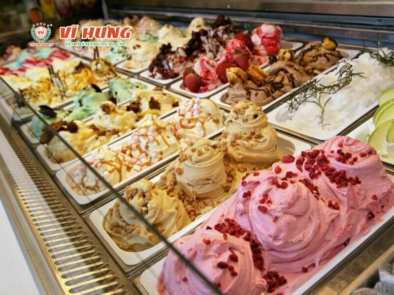 Tủ kính trưng bày buffet kem với hàng chục khay gelato nhiều màu sắc được trang trí công phu bằng dâu tây, hạt lựu, kẹo marshmallow và các topping đa dạng.