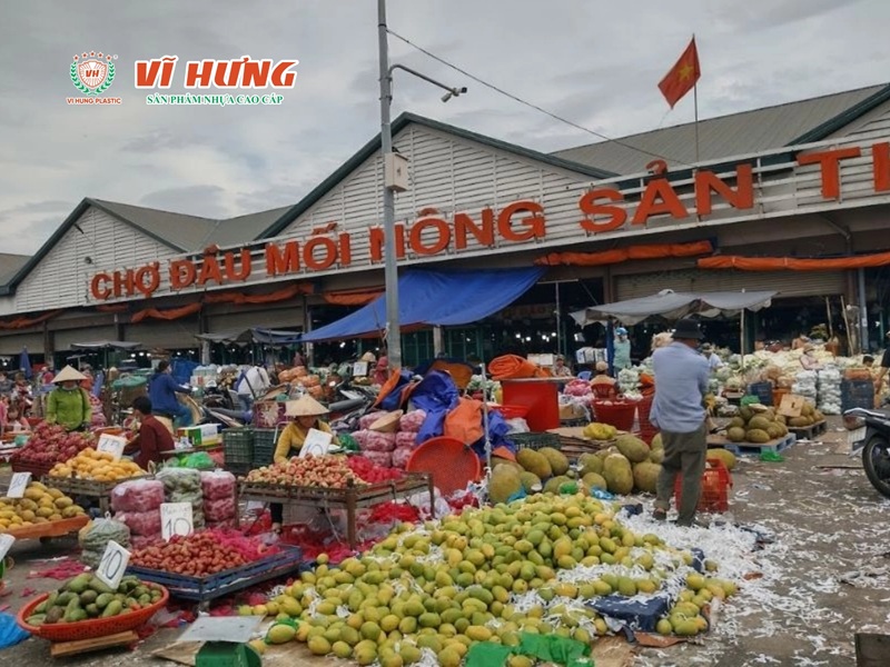 Chợ đầu mối trái cây với nhiều thùng hàng xếp chồng, người buôn đang lựa trái cây