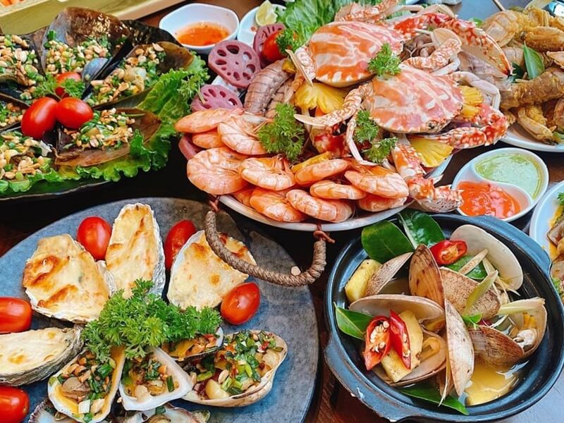 Bàn buffet hải sản tầm trung với cua, tôm, hàu nướng, nghêu và sashimi cá hồi được bày trí đẹp mắt
