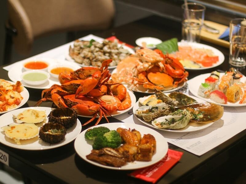 Bàn buffet hải sản cao cấp với tôm hùm, cua hoàng đế, hàu và sushi trong không gian nhà hàng sang trọng