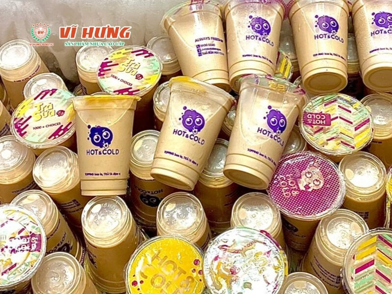 Nhiều hộp trà sữa được đóng gói trong các hộp giấy và túi nhựa có in logo thương hiệu màu tím và vàng, sắp xếp chật chội thể hiện quy mô sản xuất lớn