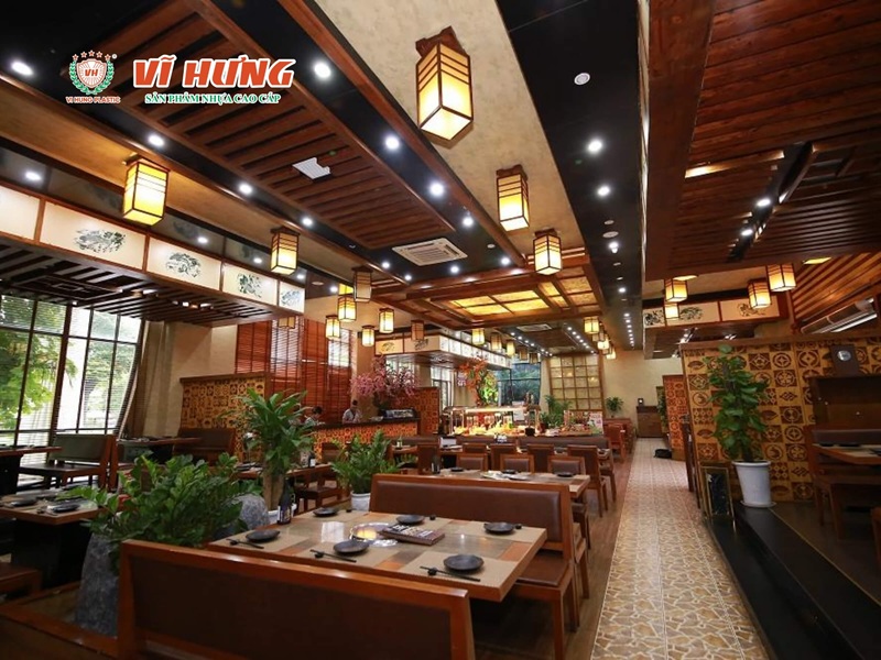 Không gian nhà hàng lẩu nướng cao cấp với nội thất gỗ tối màu, đèn lồng trang trí và bàn ghế đồng bộ sang trọng trong không gian rộng nhiều bàn.