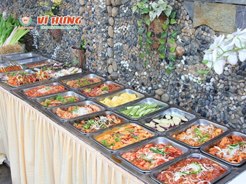 Bàn buffet tự chọn với nhiều khay món ăn đa dạng được bày trí tại một nhà hàng quy mô nhỏ