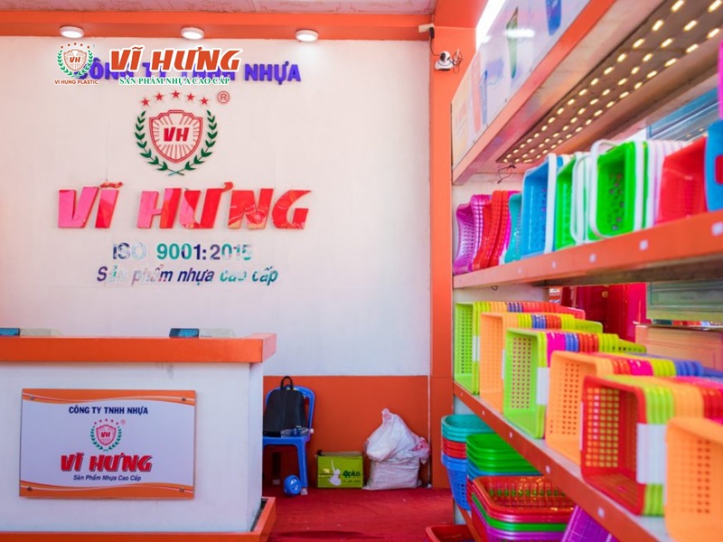 Showroom nhà máy Nhựa Vĩ Hưng với logo lớn, kệ hàng nhựa đầy màu sắc và quầy lễ tân chuyên nghiệp